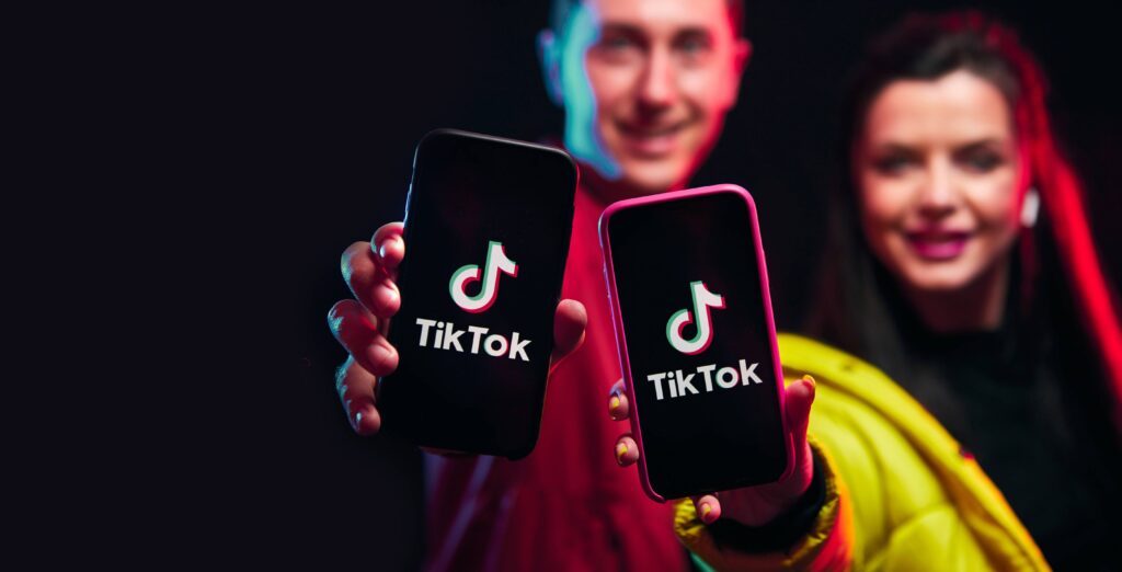 Two people holding phones with the TikTok logo on the screens