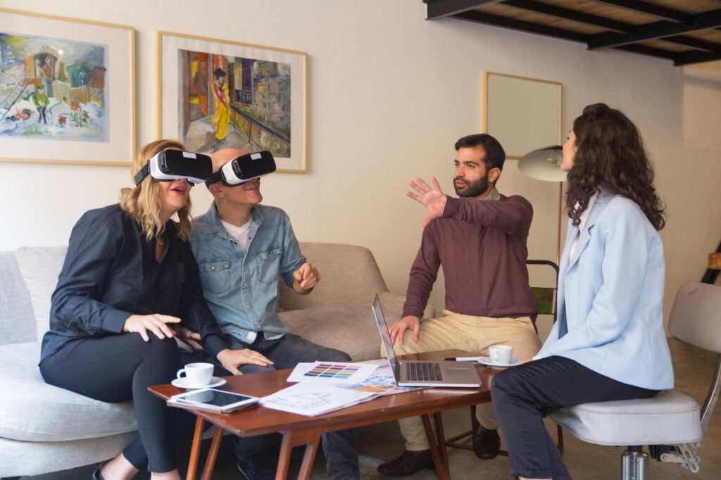 In the picture, there is a group of people gathered around a table. Two persons are wearing a VR headset, suggesting they may be experiencing virtual reality.